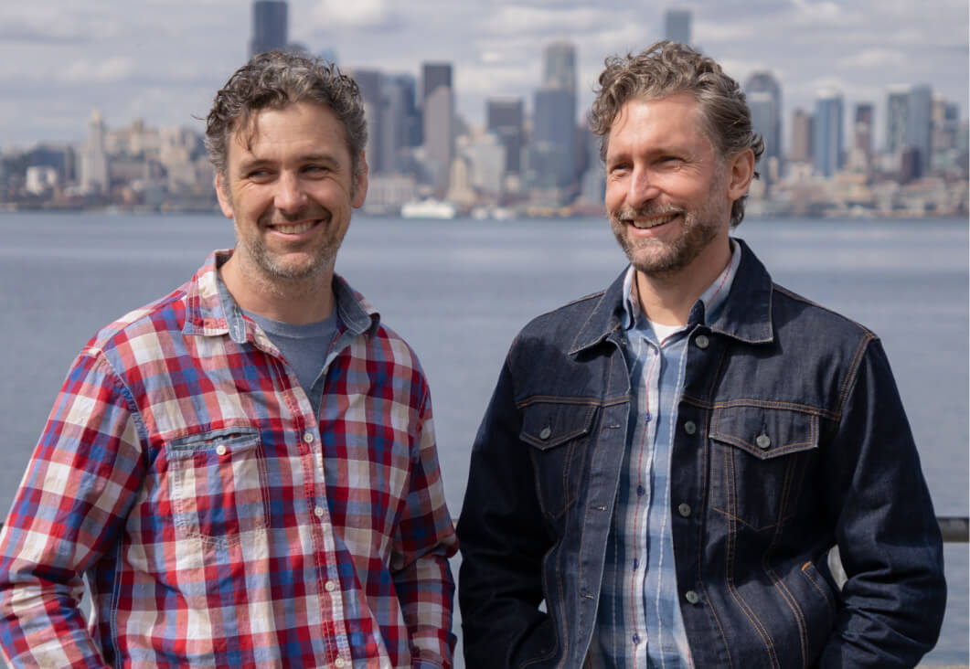 Portrait of business owners Ian and Alex against the Seattle skyline